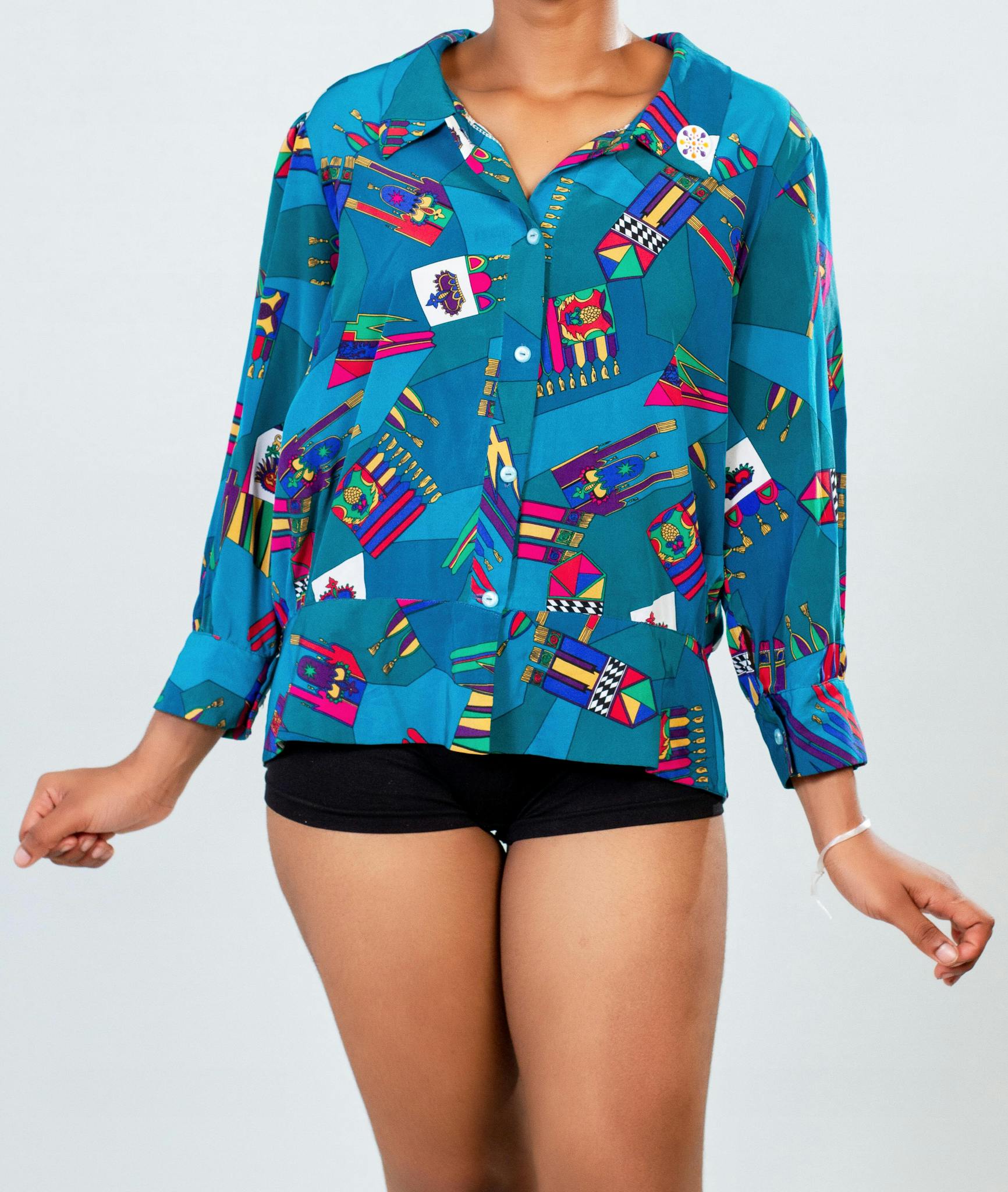 Fashionable model in a colorful patterned shirt posing stylishly in a studio setting.
